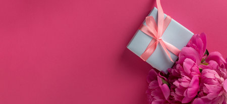 Valentines Day Background with Pink Peonies and Gift Box With Satin Pink Bow on a Magenta Color Background.の写真素材