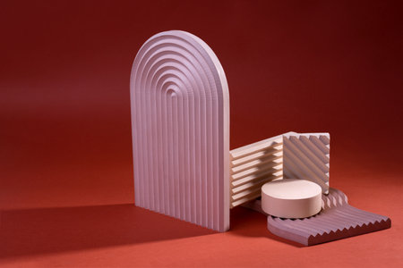 Composition of geometric podiums or pedestals in dirty pink color against red. Minimal background for cosmetic product presentation display.の写真素材