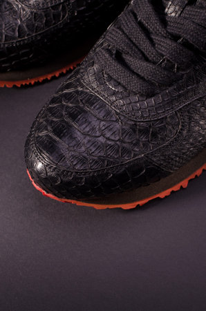 Fashionable genuine leather sneakers on a black background. Fashionable footwear.