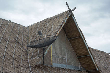 satellite dish on  thatched roofの写真素材