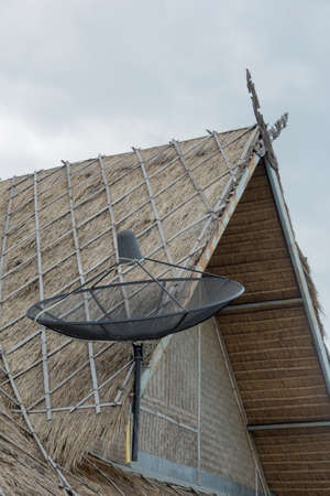 satellite dish on  thatched roofの写真素材