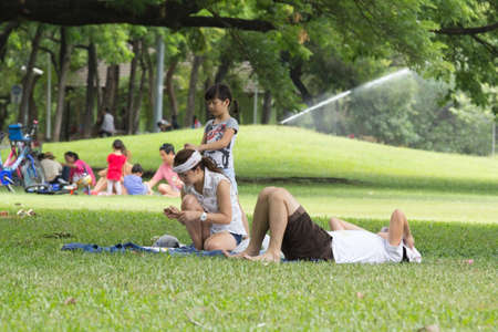 BANGKOK THAILAND - July 5. Family relaxing on the grass at the Vachirabenjatas Park Rot Fai park of Bangkok on July 5, 2015 in Bangkok, Thailandのeditorial素材