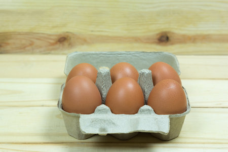 fresh eggs in cardboard package on wooden background