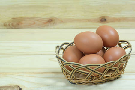 closeup fresh eggs in basket on wooden backgroundの写真素材