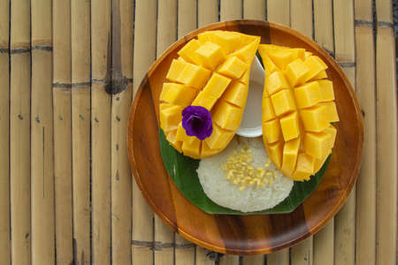 top view of fresh ripe mango and sticky rice with coconut milk on bamboo background, traditional Thai dessertの写真素材