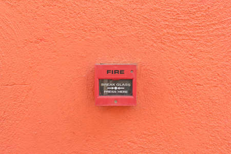 fire alarm box on orange wall backgroundの写真素材