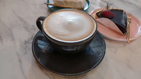 closeup cup of coffee on table with cake in backgroundの写真素材