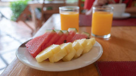 plate of pineapple and watermelon on wooden tableの写真素材