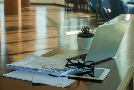 Work area with laptops and communication devices, including work documents and glasses And small potted trees to relaxの写真素材