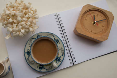 Flowers, coffee and notebooks and watches On a white wooden table that looks relaxedの写真素材