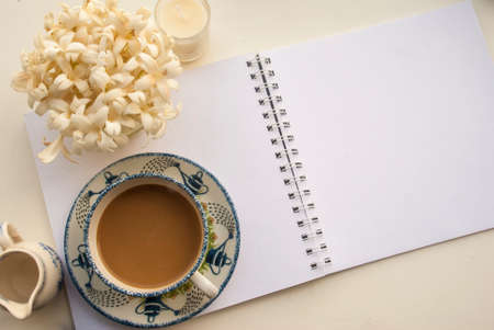 Flowers, coffee and notebooks on a white wooden table that looks relaxedの写真素材