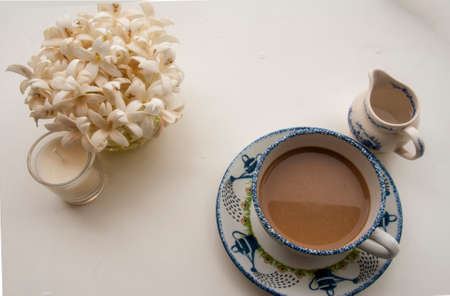 Flowers, coffee and notebooks on a white wooden table that looks relaxedの写真素材