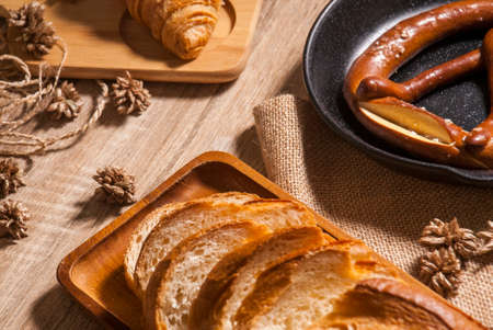 New baked bread, both croissants, French bread and pretzel, placed on trays and chopping boards and wooden tables for customer serviceの写真素材