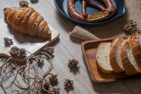 Pretzel and baguette and fresh croissants are placed on a wooden table to wait for customers to buy and eat.の写真素材