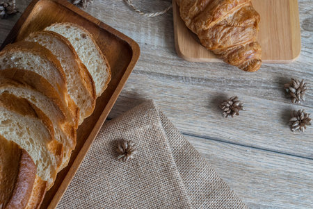 Baguette sliced ââtogether with a fresh croissant, placed on a wooden table with a sackcloth, placed for customer service from the top view.の写真素材