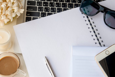 Laptops and flowers, glasses, notebooks and pens Scented candles on a white table that look relaxed