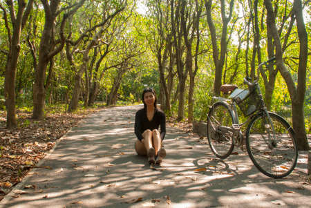 Asian women sitting while resting from cycling in the parkの写真素材