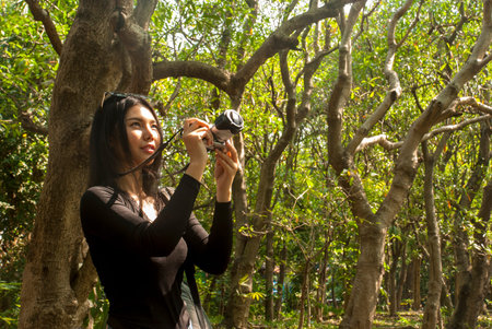 The young traveler, who is traveling, is lifting the camera during a walk in the garden.