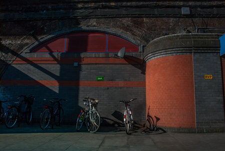 The bicycle is parked at the station in front of the concrete wall in London.