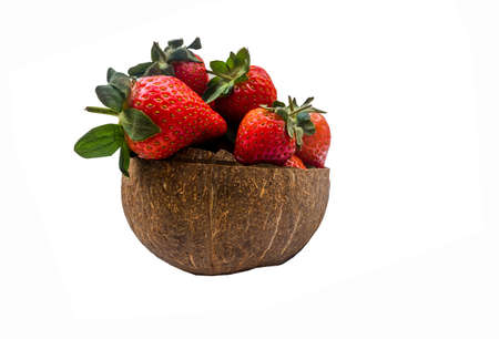 Fresh strawberries in a coconut shell on white background.の写真素材