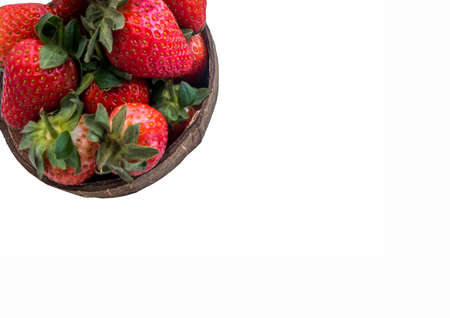 Fresh strawberries in a coconut shell on white background.の写真素材