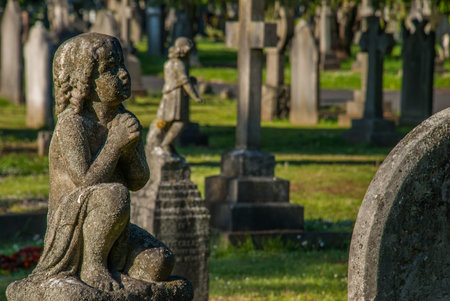 The ancient statue of the boy is asking for blessings from God in the North Sheen cemetery.