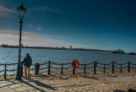 The young man stood alone under the Street lamp on the river walk Suitable for background images.の写真素材