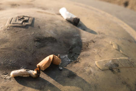 Public metal ashtray with extinguished cigarette butts and ash.の写真素材