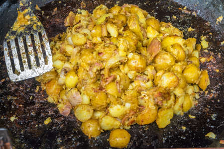 Potatoes with bacon and brie in a frying pan.の写真素材