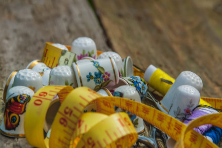 Spools of thread and basic sewing tools including pins, needle, a thimble, and tape measure on an...