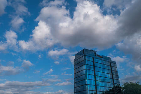 London - 5 May 2019 Angular geometric mirror cladding on a modern building with repeating structure and reflected sky and clouds.のeditorial素材