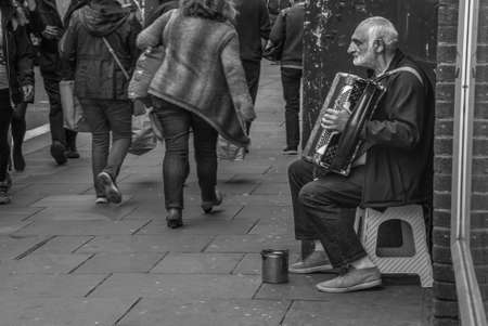 London - May 5, 2019 - Beggar or homeless man play music exchange money, Beggars on the streets of the city, Black and white., Social problems concept.のeditorial素材