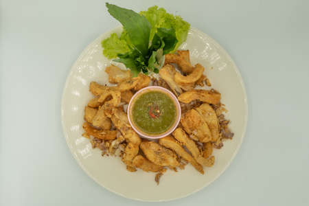 Deep fried salmon bellies or crispy salmon belly with spicy sauce on a white dish, Top view.の写真素材
