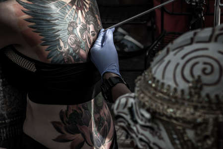 Bangkok, Thailand - 25 Aug 2019 : Tattooing Thai style concepts. Tattoo thai artist creating tattooing on body sexy woman in a creative design work studio. Process decoration ink artwork female skin pattern.のeditorial素材
