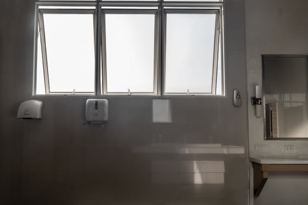 Light white bathroom interior with window and frameless mirror paired view and equipment with...