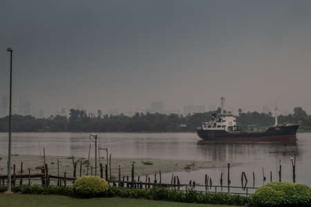 Bangkok, Thailand - 29 September 2019 : A cargo ship is parked in the middle of the river and in front of a green garden beside the Chao Phraya River.のeditorial素材