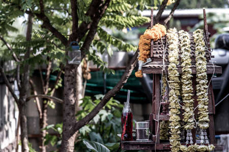 Spirit house and tree roots intertwined. Miniature house for guardian spirit with garland and some wreathes, A dedicated structure to honor the guardians of the land that is found in the Southeast Asiaの写真素材