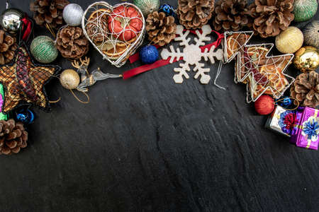 Wide arch shaped Christmas decoration border. Twigs christmas tree, brown natural pine cones and and Xmas deer with variety of fruits on dark background. Top view, Copy space.の写真素材
