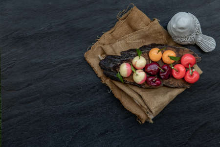 Kanom Look Choup : An old traditional thai dessert made from green been, coconut milk, sugar and jelly, Deletable imitation fruits made from green been, coconut milk, sugar and jelly in fruit shape on wooden, It is a unique dessert of Thailand, Top view.の写真素材