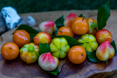Close up of Kanom Look Choup : An old traditional thai dessert made from green been, coconut milk, sugar and jelly, Deletable imitation fruits made from green been, coconut milk, sugar and jelly in fruit shape on wooden, It is a unique dessert of Thailand.の写真素材