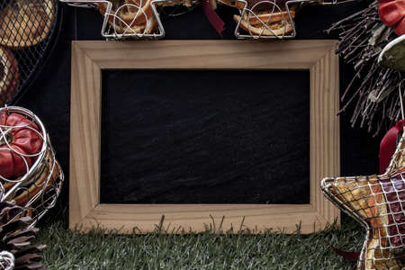 Christmas decoration, Brown natural pine cones and variety of fruits with Empty wooden frame for work about design element on lawn and dark background, Copy Space.の写真素材