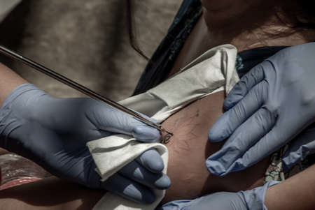 Bangkok, Thailand - 25 Aug 2019 : Tattooing Thai style concepts. Tattoo artist creating a tattoo on a girl's arm with a pointed metal.のeditorial素材