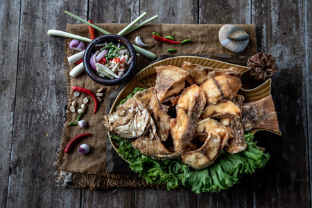 Deep fried Tubtim fish with fish sauce on vintage wooden, The perfect frying process, Set hot fire, then bring the Tubtim fish to fry to frame and topped with fish sauce.の写真素材