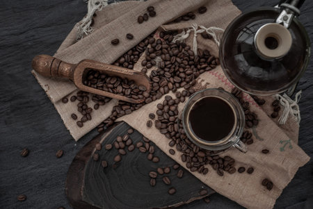 Coffee style, Cup of coffee and coffee beans roating with old wooden scoop and coffee beans around...