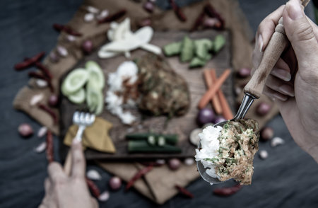 A local Thai food style, The hand is using a spoon to scoop fried acacia pennata omelet or cha-om...