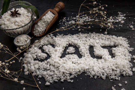 The salt crystals on black stone plate background. Healthy sea salt. Vintage style, Selective focus.の写真素材