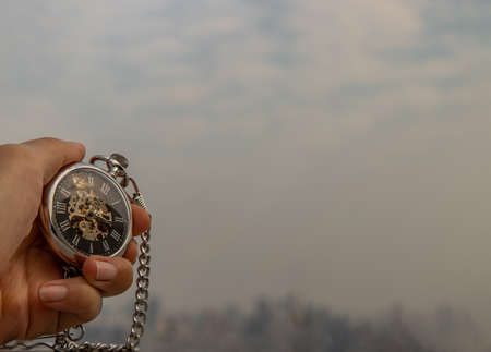 A retro pocket watch with chain in the palm of the girl's hand. Sky background. Copy space.の写真素材