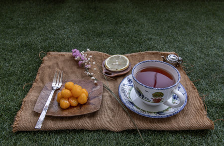 Lunch - Tea and Lemon Served with Thongyod (Thai Desserts) on Green lawn in the park. Copy space, Selective focus.の写真素材