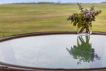 A beautiful purple flower bouquet in a glass vase on the glass table overlooking the garden. copy...