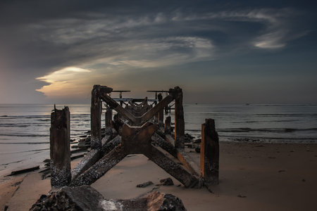 Looking out at Broken old structure remains of pier in the sea. Small wave crashing into the...